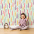 Lovely child standing in front of Whimsy Tots Feather and Arrow Meadow Parade Wallpaper in Soft Mint Green with feather, arrow, leaf in design. Lovely child standing in front of Whimsy Tots Feather and Arrow Meadow Parade Wallpaper in Soft Mint Green with feather, arrow, leaf in design.
