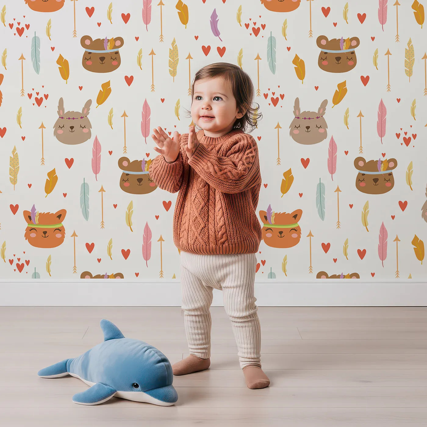 Lovely child standing in front of Whimsy Tots Woodland Tribe Hearts Wallpaper in Soft White with bear, fox, rabbit, feather, arrow, heart in design.
