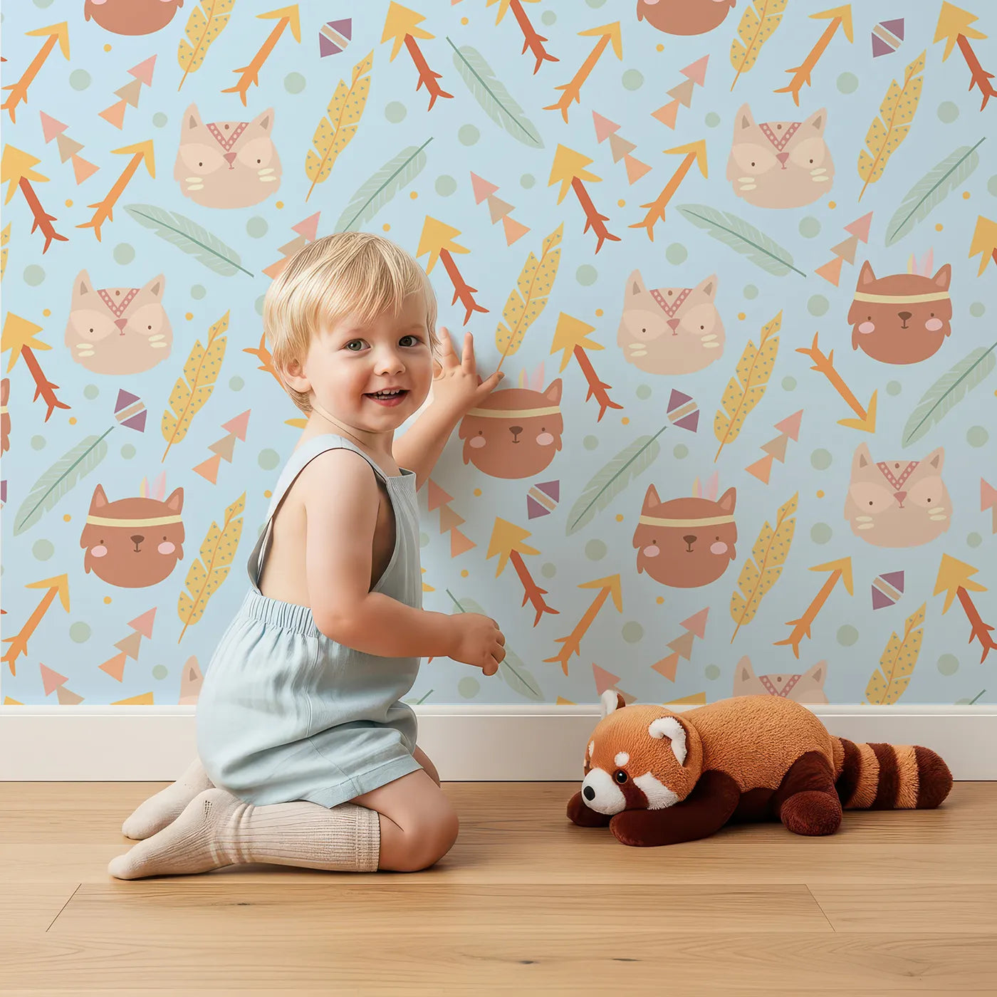 Lovely child standing in front of Whimsy Tots Tribal Kitten Parade Wallpaper in Sky Blue with cat, feather, arrow, triangle, dot in design.
