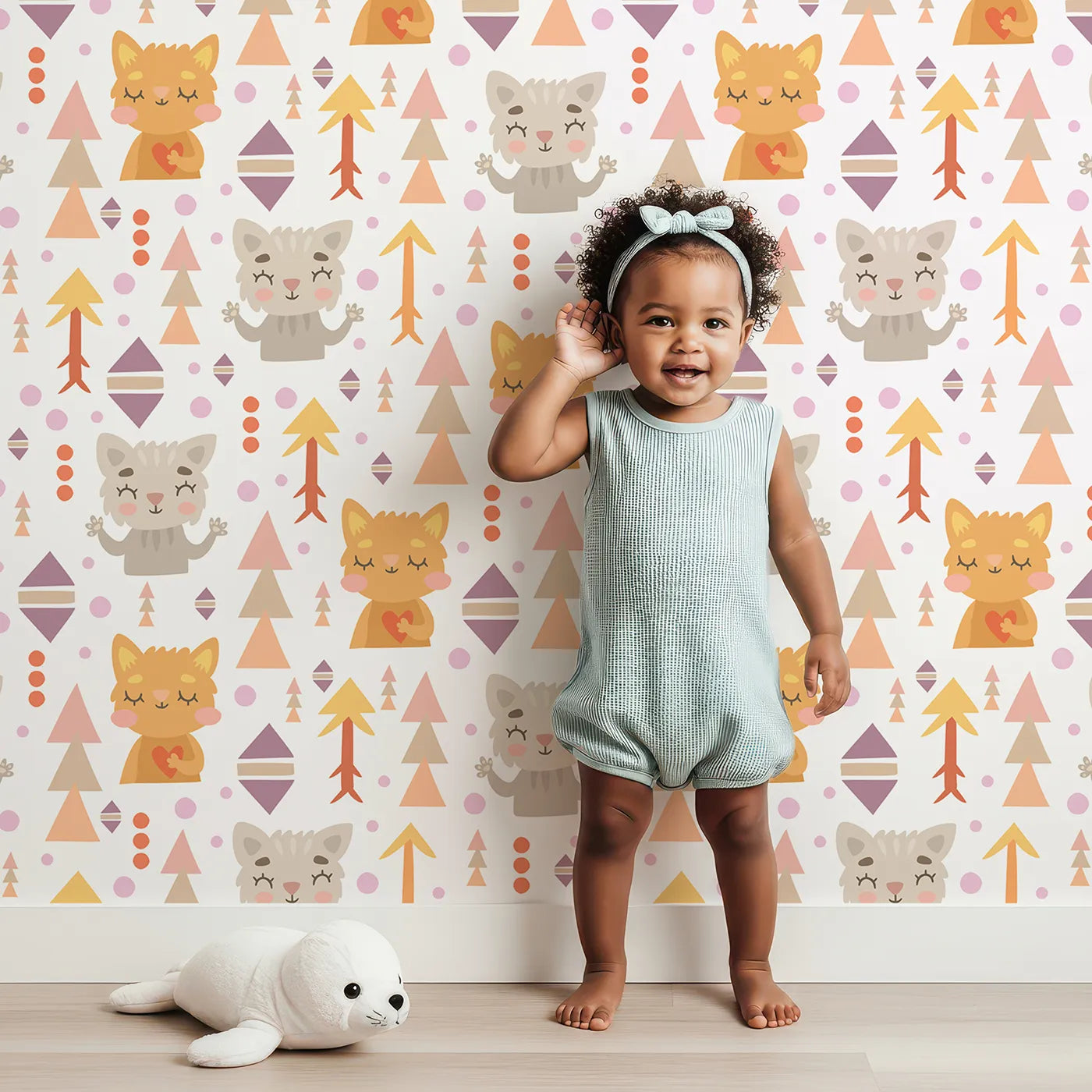 Lovely child standing in front of Whimsy Tots Mindful Kitten Heart Wallpaper in Vanilla Cream with cat, heart, triangle, dot, diamond in design.