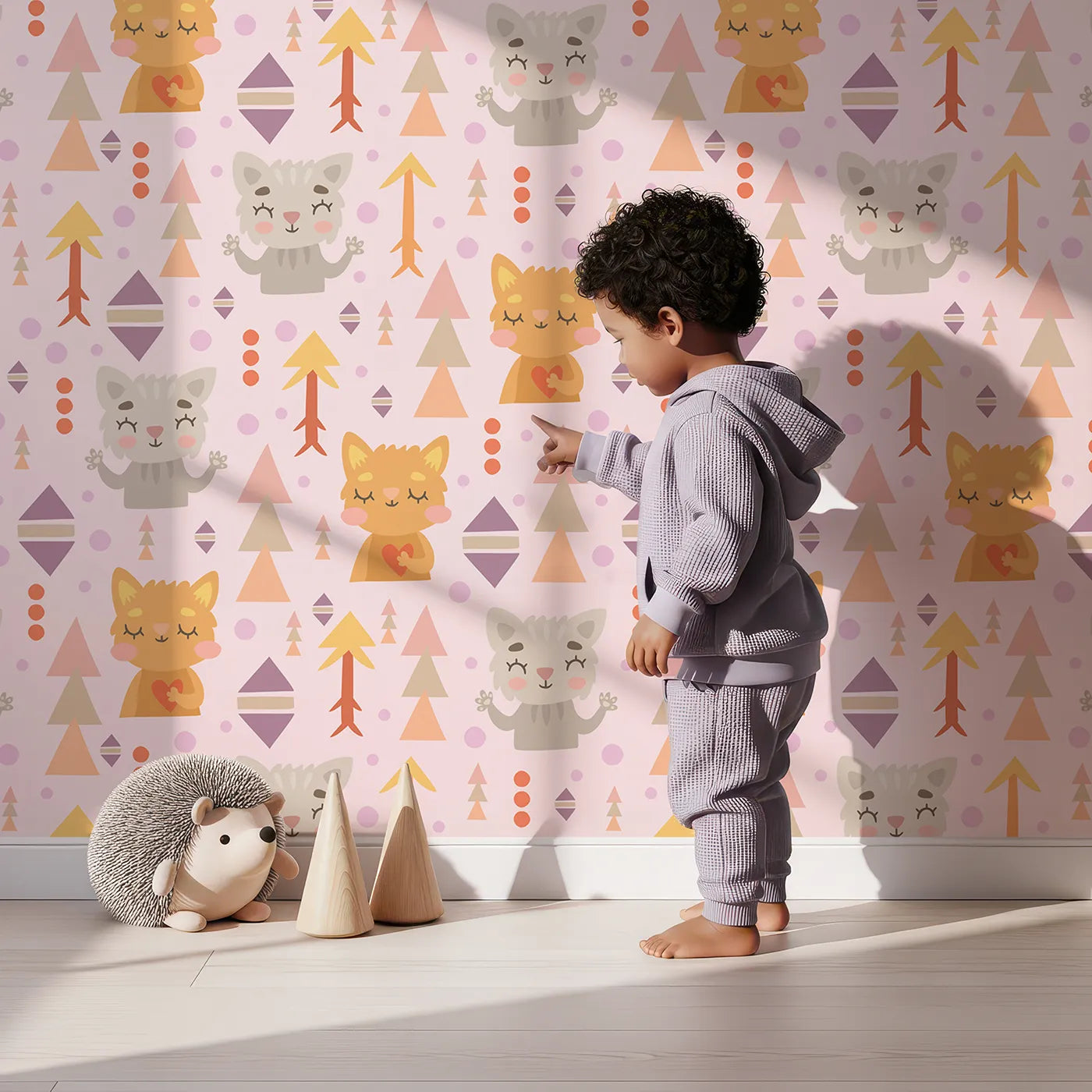Lovely child standing in front of Whimsy Tots Mindful Kitten Heart Wallpaper in Petal Blush Pink with cat, heart, triangle, dot, diamond in design.