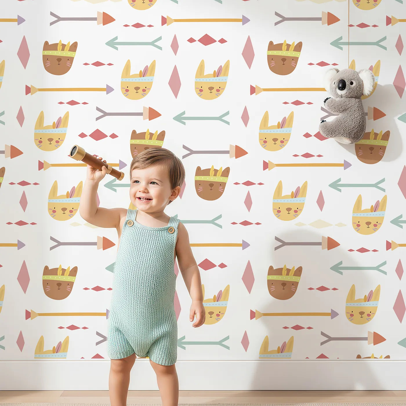 Lovely child standing in front of Whimsy Tots Tribal Bunny Parade Wallpaper in Vanilla Cream with rabbit, arrow, feather, diamond in design.