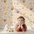 Lovely child standing in front of Whimsy Tots Tribal Bunny Parade Wallpaper in Oat Beige with rabbit, arrow, feather, diamond in design. Lovely child standing in front of Whimsy Tots Tribal Bunny Parade Wallpaper in Oat Beige with rabbit, arrow, feather, diamond in design.