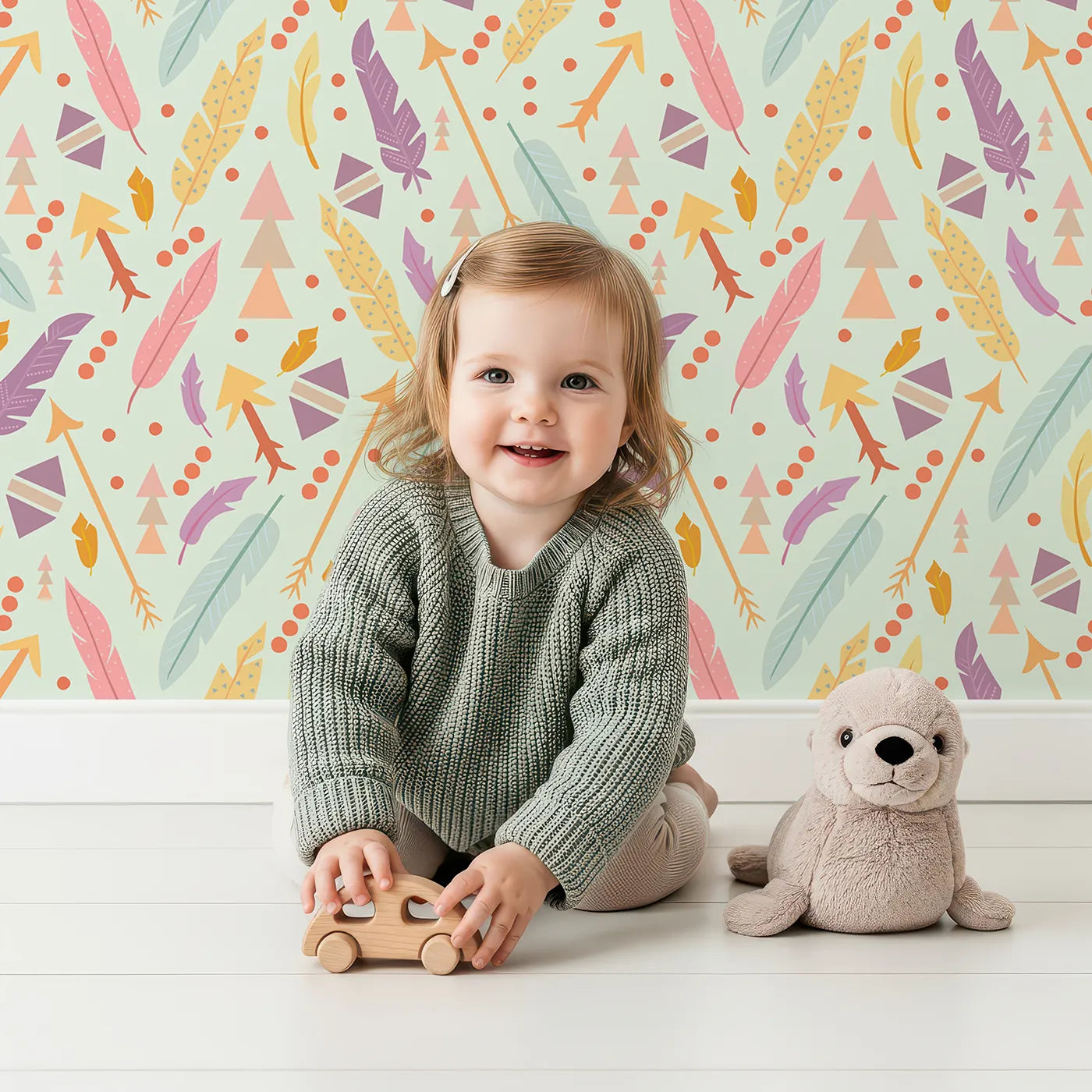 Lovely child standing in front of Whimsy Tots Feather Arrow Confetti Wallpaper in Mint Whisper Green with arrow, feather, triangle, dot in design.