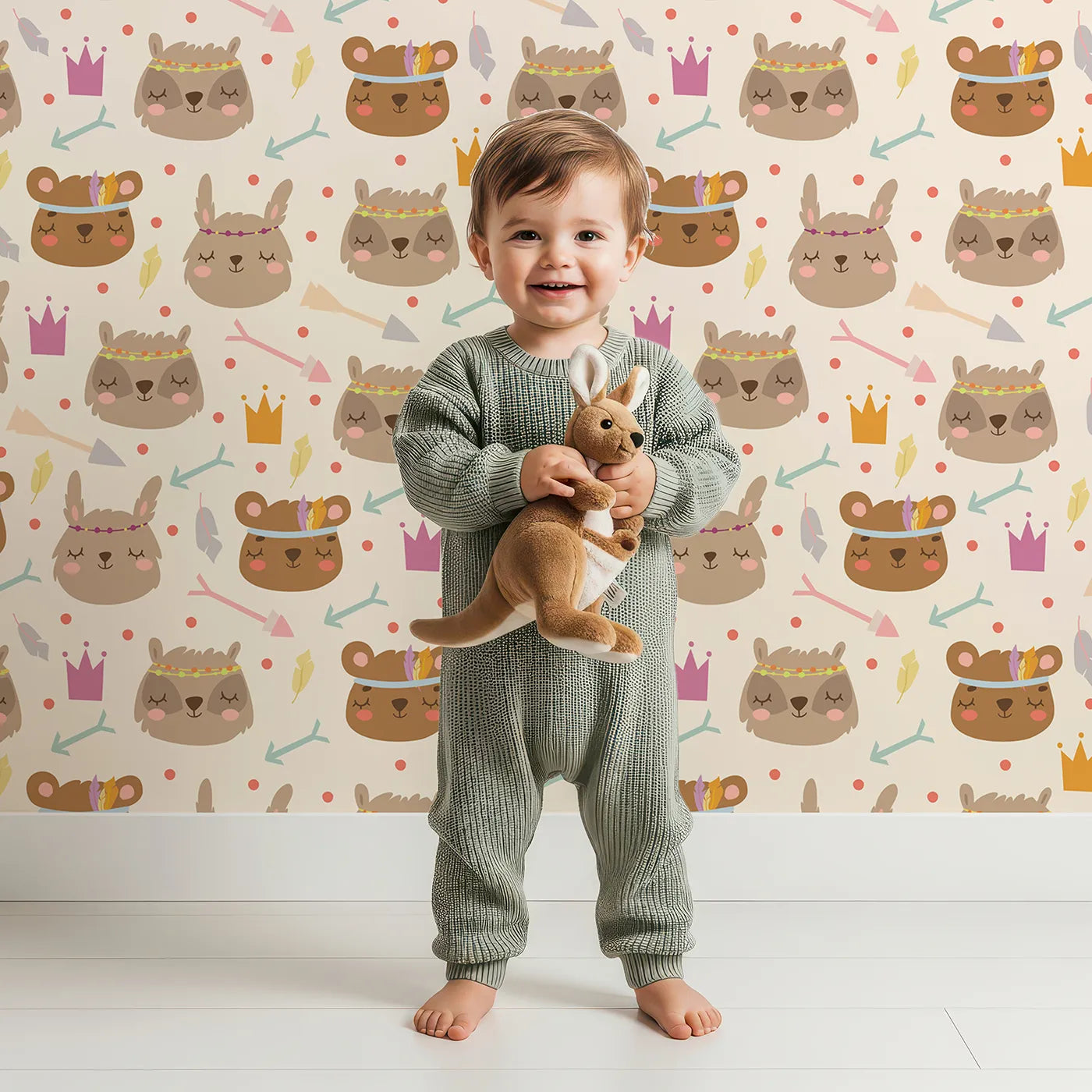 Lovely child standing in front of Whimsy Tots Feather Crown Critters Wallpaper in Beige with bear, rabbit, crown, feather, arrow, dot in design.