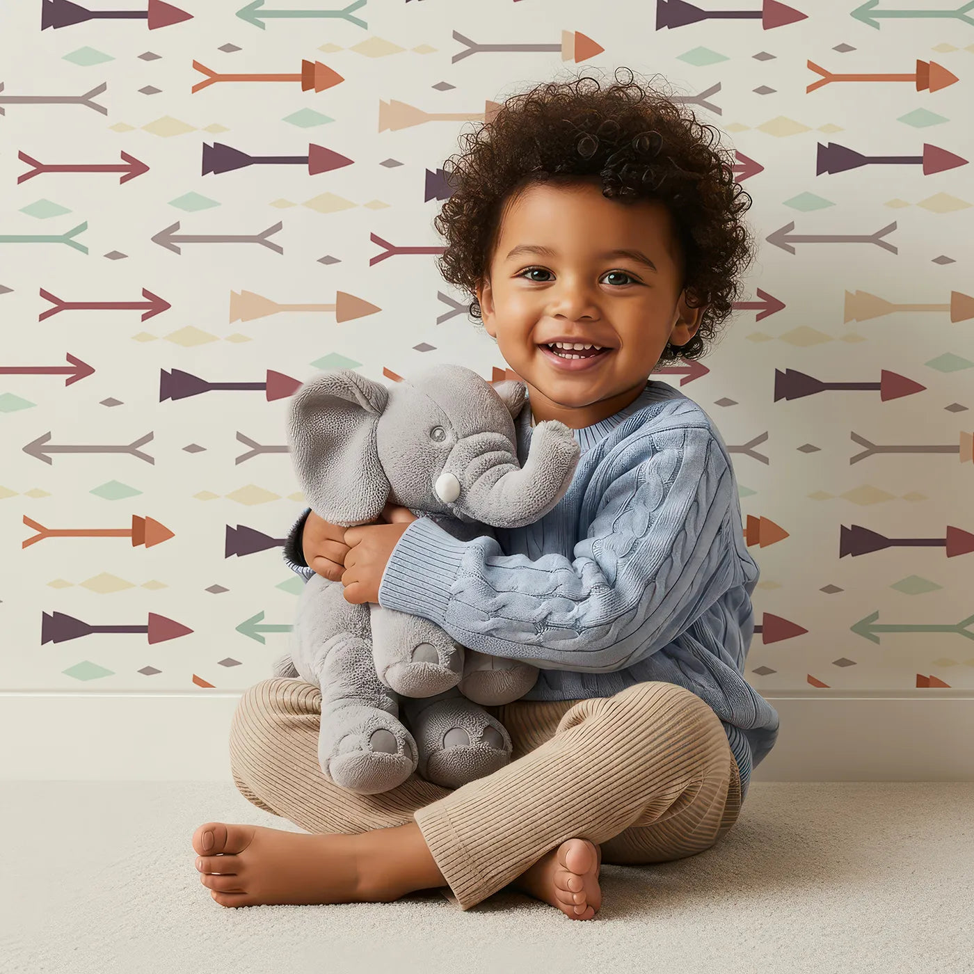 Lovely child standing in front of Whimsy Tots Boho Arrow Trail Wallpaper in Cream White with arrow, diamond in design.