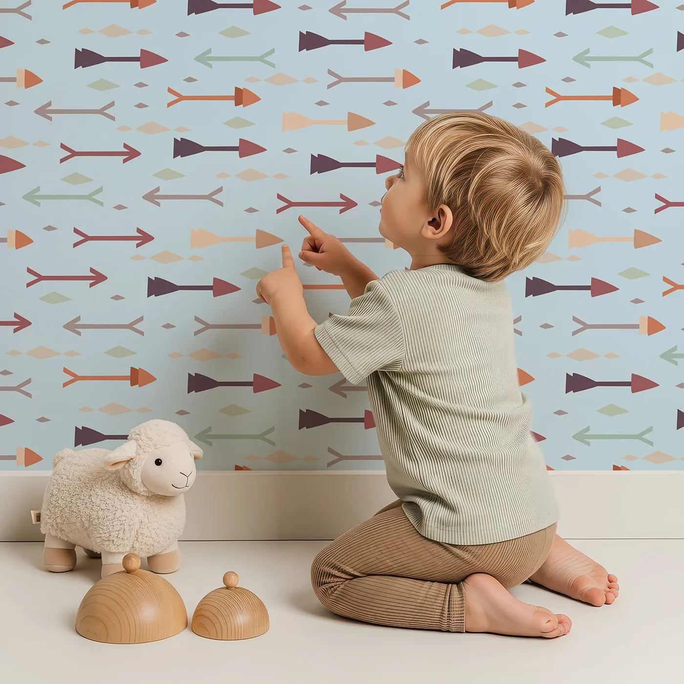Lovely child standing in front of Whimsy Tots Boho Arrow Trail Wallpaper in Soft Sky with arrow, diamond in design.