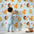 Lovely child standing in front of Whimsy Tots Cuddle Buddies Parade Wallpaper in Blue with fox, bird, badger, cat, heart, flower in design. Lovely child standing in front of Whimsy Tots Cuddle Buddies Parade Wallpaper in Blue with fox, bird, badger, cat, heart, flower in design.