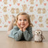 Lovely child standing in front of Whimsy Tots Heartful Bunny Parade Wallpaper in White with rabbit, heart in design. Lovely child standing in front of Whimsy Tots Heartful Bunny Parade Wallpaper in White with rabbit, heart in design.