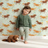 Lovely child standing in front of Whimsy Tots Dreamy Pony Meadow Wallpaper in Soft Mint Green with horse, flower, leaf, dot in design. Lovely child standing in front of Whimsy Tots Dreamy Pony Meadow Wallpaper in Soft Mint Green with horse, flower, leaf, dot in design.