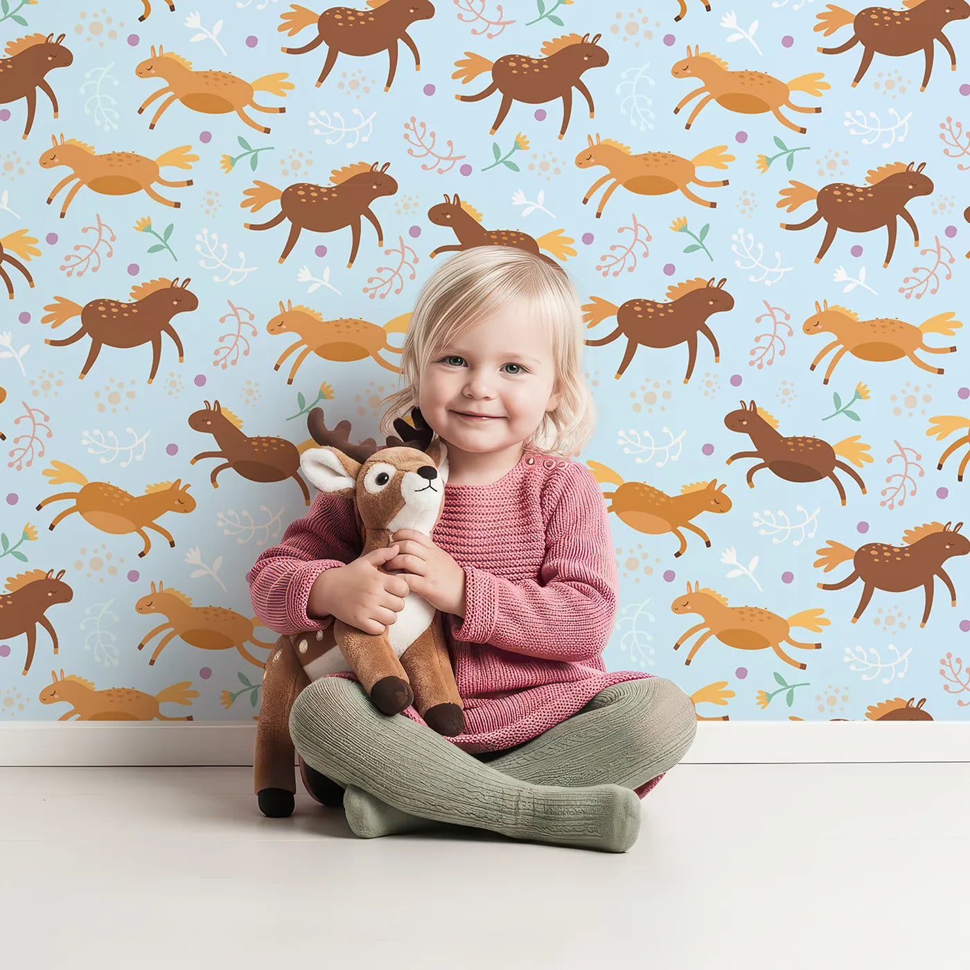 Lovely child standing in front of Whimsy Tots Dreamy Pony Meadow Wallpaper in Sky Blue with horse, flower, leaf, dot in design.