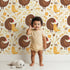 Lovely child standing in front of Whimsy Tots Hen and Chick Meadow Wallpaper in Cream Nest with chicken, chick, flower, leaf in design. Lovely child standing in front of Whimsy Tots Hen and Chick Meadow Wallpaper in Cream Nest with chicken, chick, flower, leaf in design.