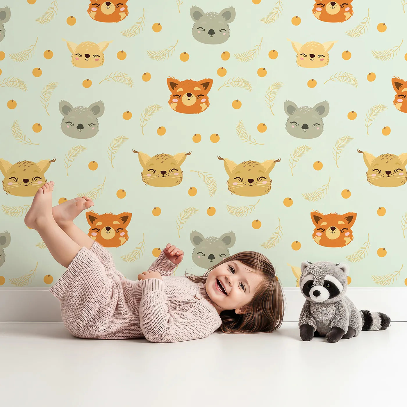 Lovely child standing in front of Whimsy Tots Outback Snuggle Faces Wallpaper in Mint Meadow Green with koala, fox, lynx, feather, berry in design.