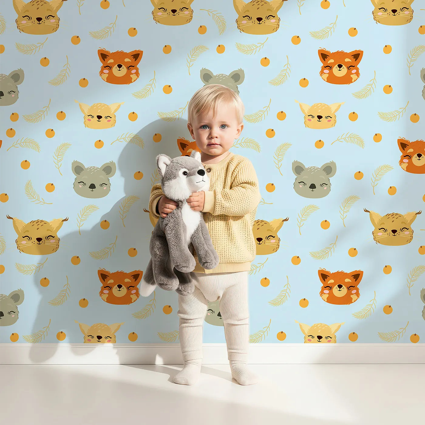 Lovely child standing in front of Whimsy Tots Outback Snuggle Faces Wallpaper in Sky Blue with koala, fox, lynx, feather, berry in design.