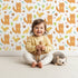 Lovely child standing in front of Whimsy Tots Fox and Finch Woodland Waltz Wallpaper in White with fox, bird, acorn, leaf, flower in design. Lovely child standing in front of Whimsy Tots Fox and Finch Woodland Waltz Wallpaper in White with fox, bird, acorn, leaf, flower in design.