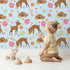 Lovely child standing in front of Whimsy Tots Blossom Meadow Deer Wallpaper in Blue with deer, flower, butterfly, heart in design. Lovely child standing in front of Whimsy Tots Blossom Meadow Deer Wallpaper in Blue with deer, flower, butterfly, heart in design.