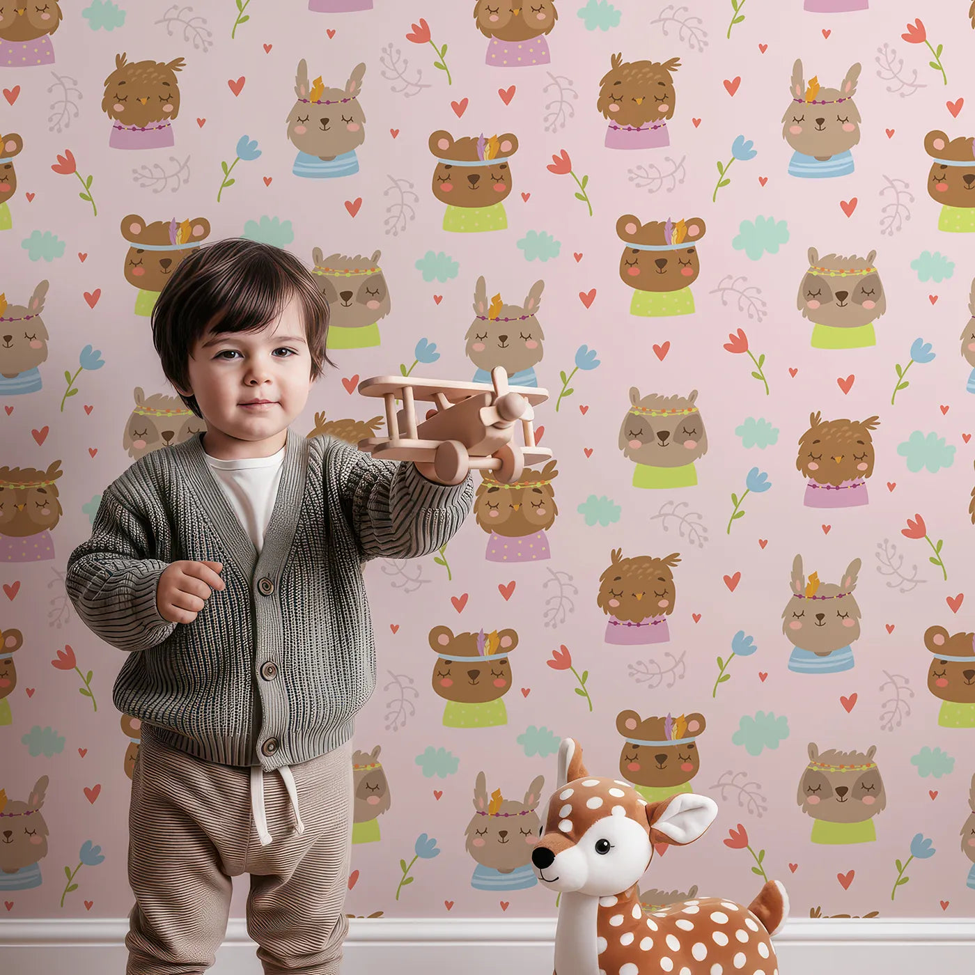 Lovely child standing in front of Whimsy Tots Heart Bloom Critters Wallpaper in Blush Pink with bear, rabbit, owl, heart, flower, cloud in design.