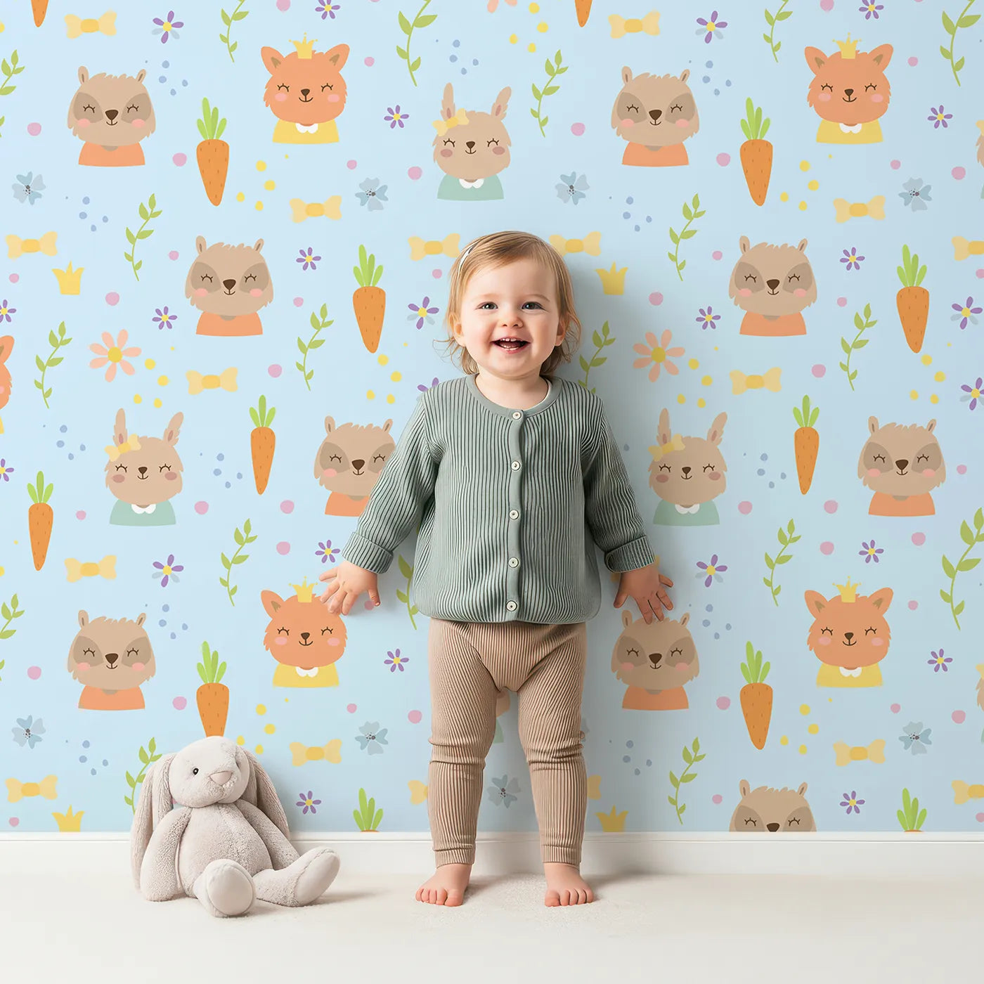 Lovely child standing in front of Whimsy Tots Meadow Crown Friends Wallpaper in Blue with fox, rabbit, bear, flower, carrot, crown, bow in design.