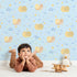 Lovely child standing in front of Whimsy Tots Snail Meadow Cuddle Parade Wallpaper in Sky Blue with snail, flower, leaf in design. Lovely child standing in front of Whimsy Tots Snail Meadow Cuddle Parade Wallpaper in Sky Blue with snail, flower, leaf in design.