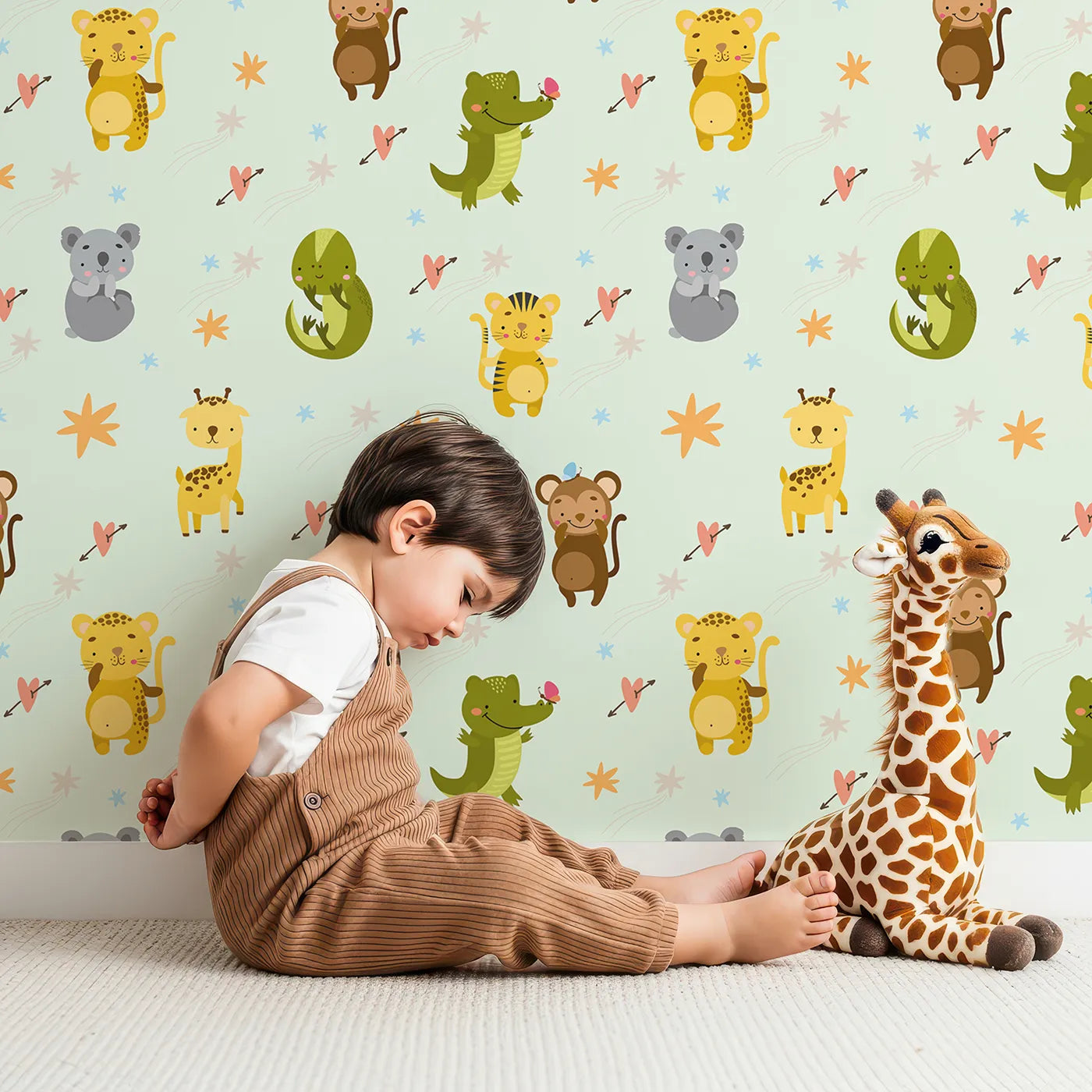 Lovely child standing in front of Whimsy Tots Wild Heart Animal Parade Wallpaper in Mint Green with giraffe, koala, leopard, monkey, tiger, crocodile, heart, arrow, star in design.