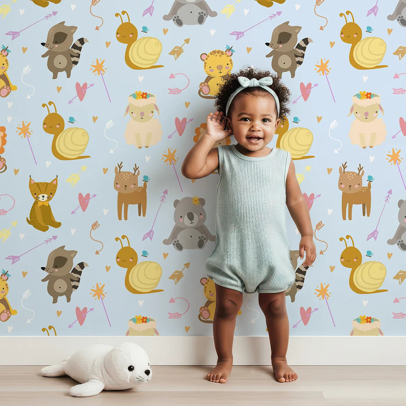 Lovely child standing in front of Whimsy Tots Magic Meadow Friends Wallpaper in Sky Blue with deer, koala, leopard, lion, raccoon, snail, arrow, wand, heart in design.