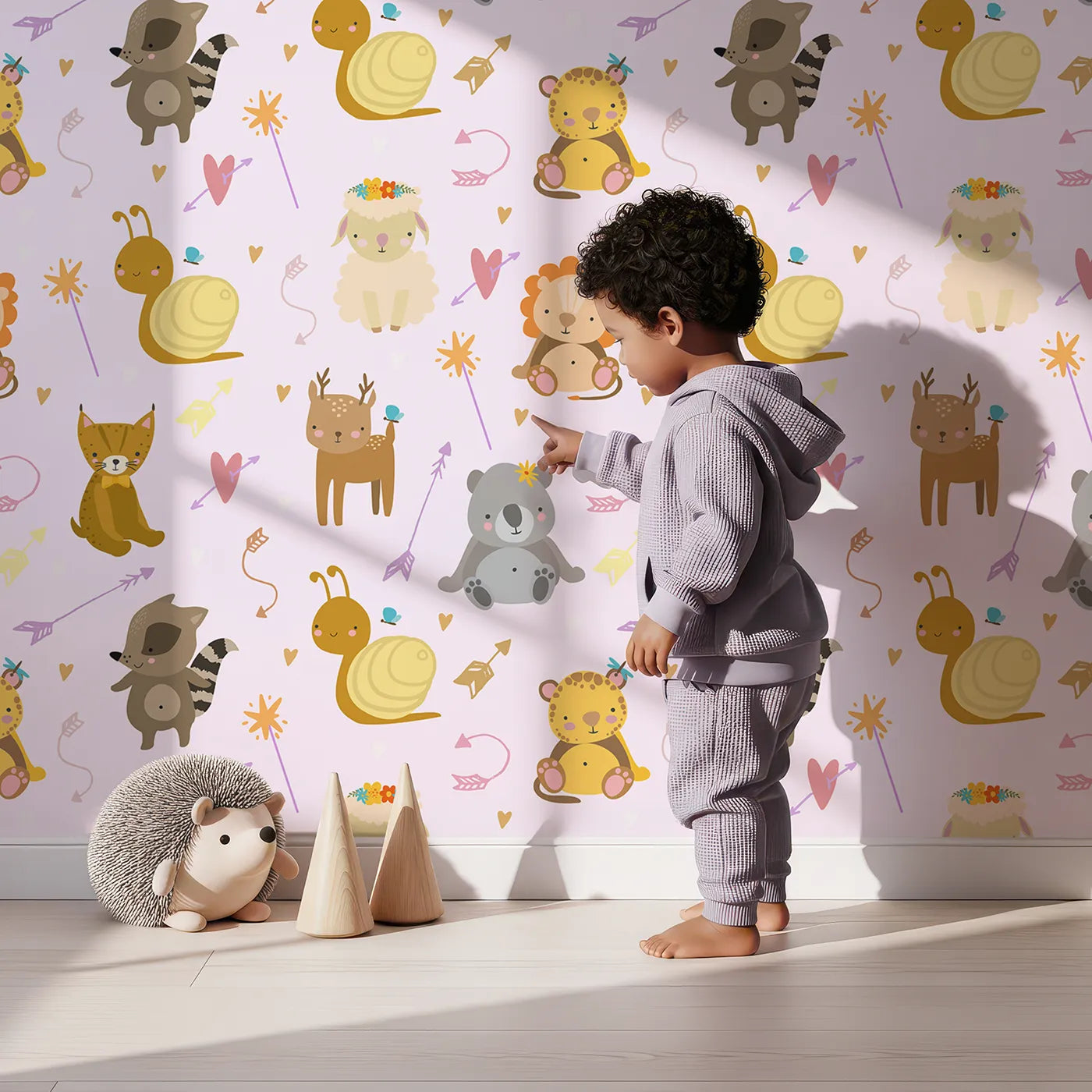 Lovely child standing in front of Whimsy Tots Magic Meadow Friends Wallpaper in Blush Pink with deer, koala, leopard, lion, raccoon, snail, arrow, wand, heart in design.