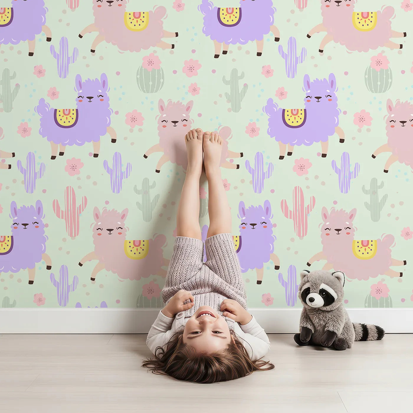 Lovely child standing in front of Whimsy Tots Bouncing Llama Fiesta Wallpaper in Mint Green with llama, cactus, flower, confetti in design.