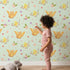 Lovely child standing in front of Whimsy Tots Tweeting Lovebirds Wallpaper in Mint Green with bird, owl, flower, heart, branch in design. Lovely child standing in front of Whimsy Tots Tweeting Lovebirds Wallpaper in Mint Green with bird, owl, flower, heart, branch in design.