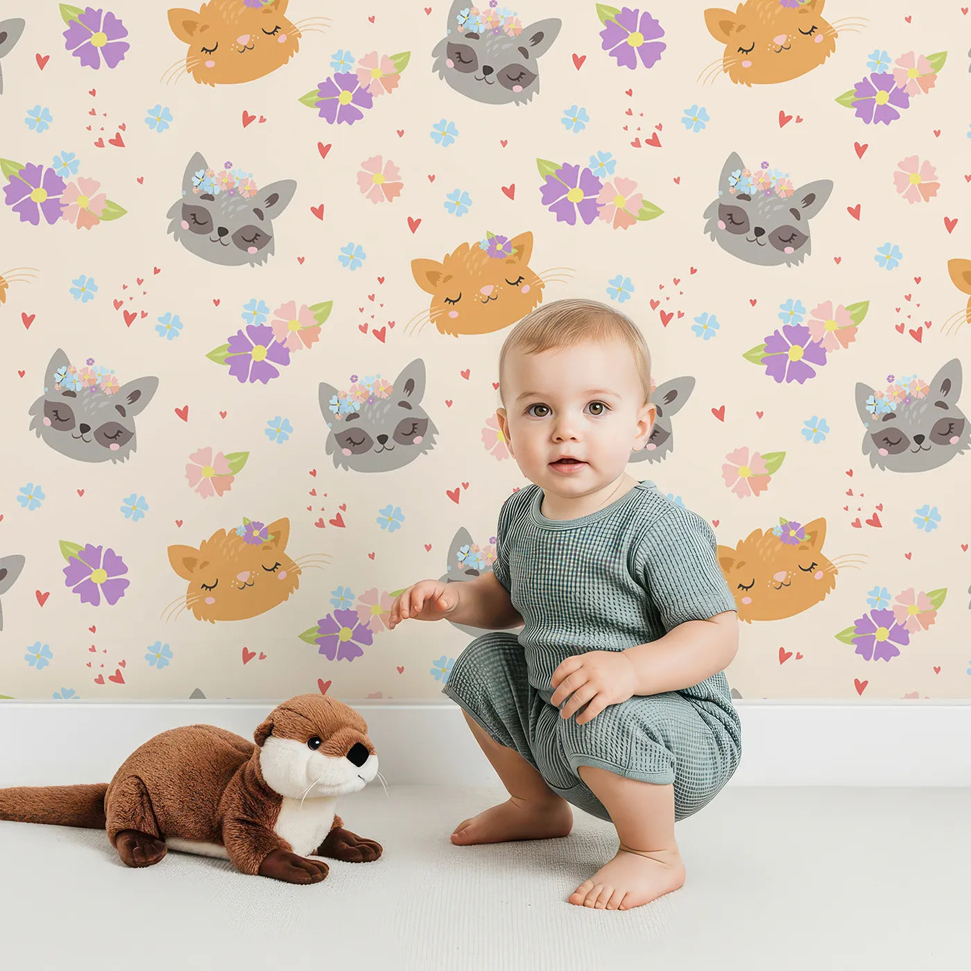 Lovely child standing in front of Whimsy Tots Meadow Snuggle Faces Wallpaper in Cream with cat, raccoon, flower, heart in design.