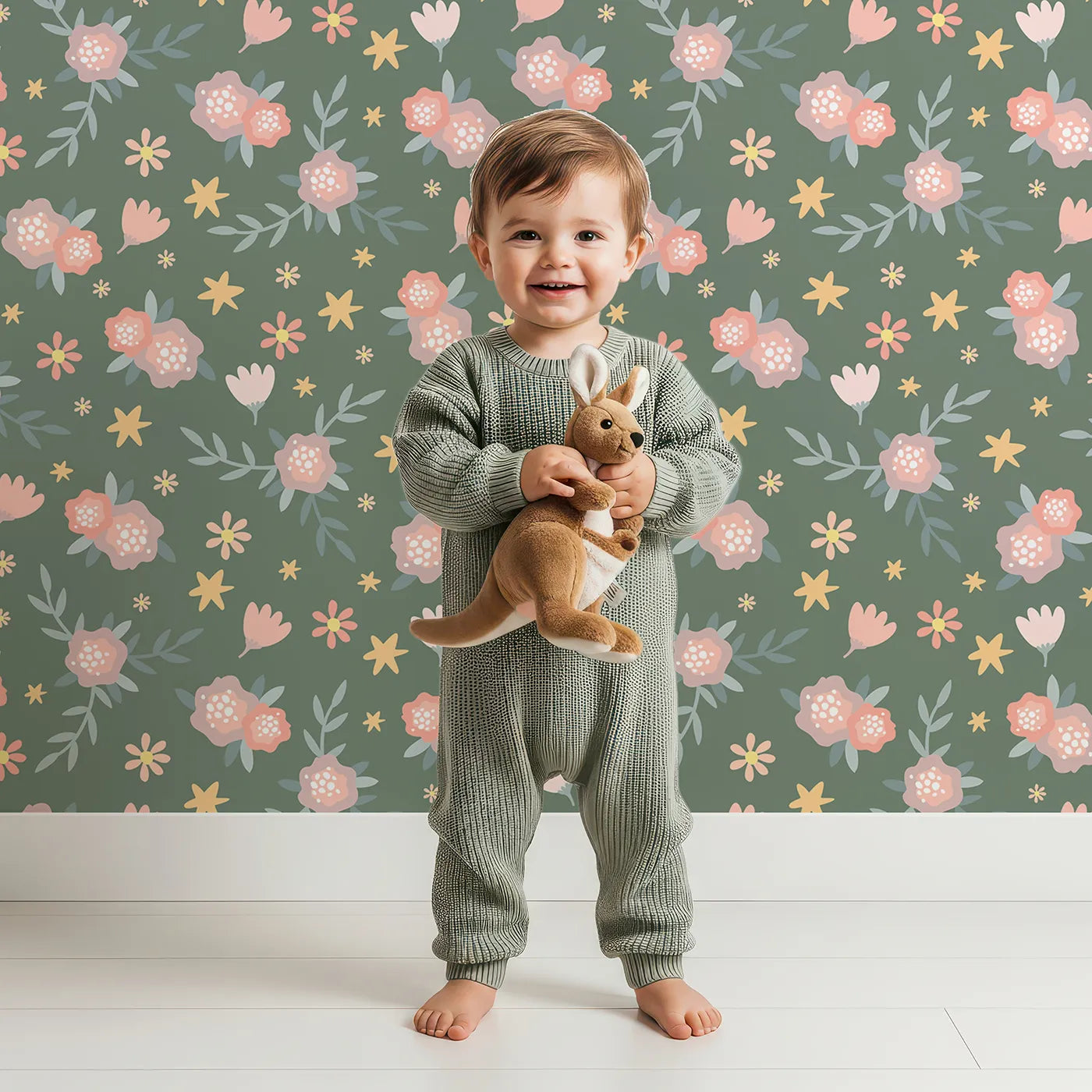 Lovely child standing in front of Whimsy Tots Twilight Wildflower Waltz Wallpaper in Forest Green with flower, star, leaf in design.