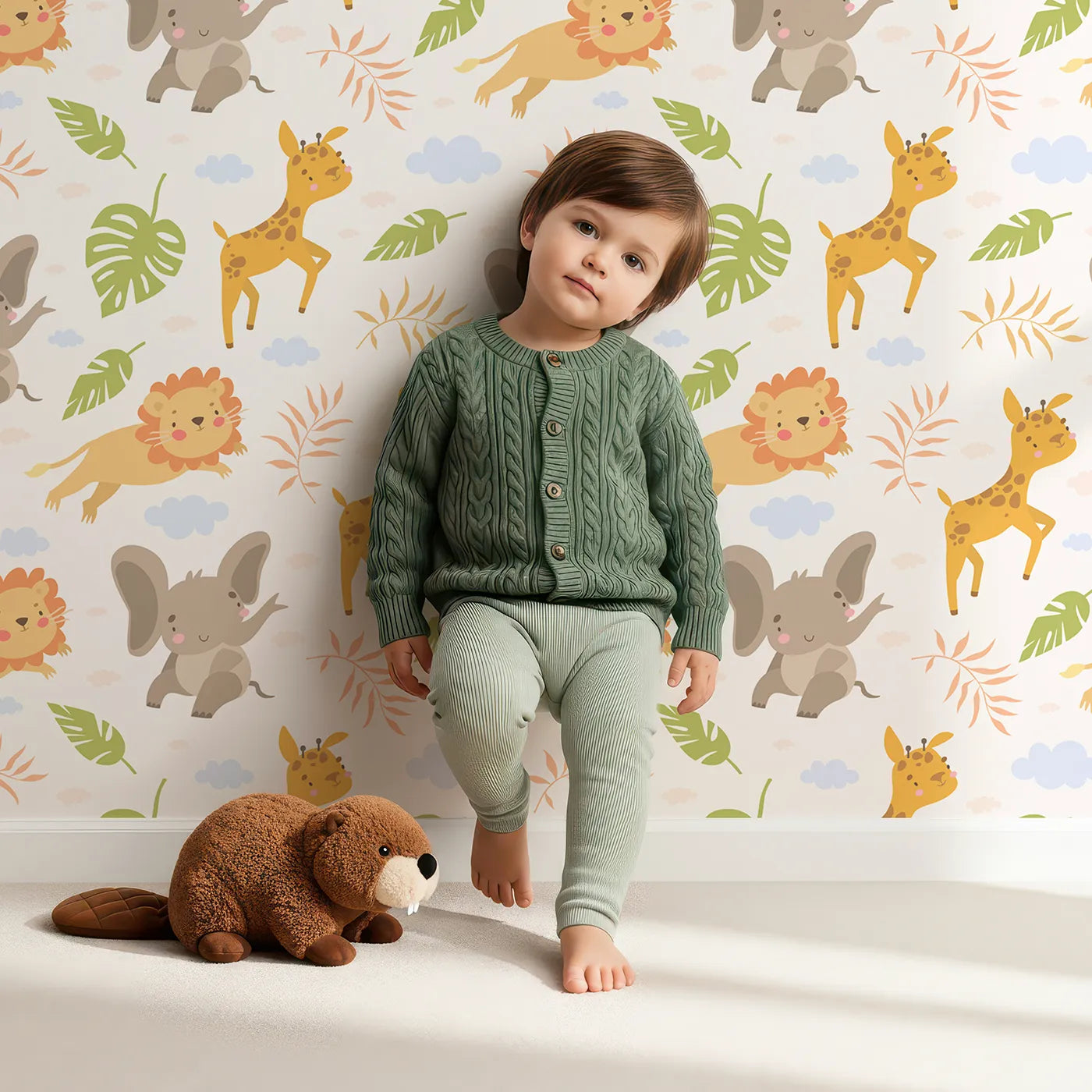Lovely child standing in front of Whimsy Tots Jungle Leaf Pals Wallpaper in Cream with lion, giraffe, elephant, leaf, cloud in design.