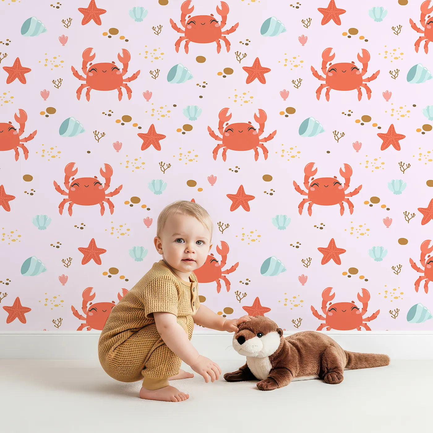 Lovely child standing in front of Whimsy Tots Crabby Coral Dance Wallpaper in Blush Pink with crab, starfish, shell, coral, sand in design.