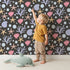 Lovely child standing in front of Whimsy Tots Starry Coral Garden Wallpaper in Charcoal Gray with starfish, coral, shell, bubble in design. Lovely child standing in front of Whimsy Tots Starry Coral Garden Wallpaper in Charcoal Gray with starfish, coral, shell, bubble in design.
