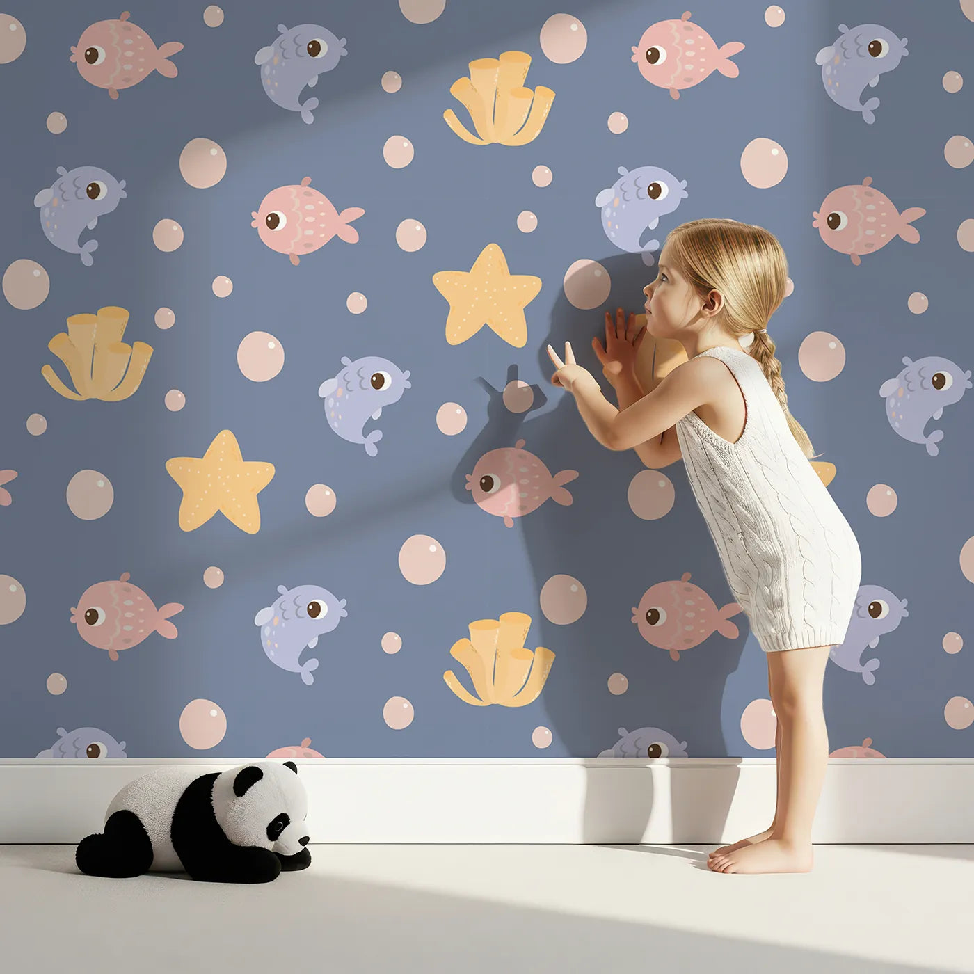 Lovely child standing in front of Whimsy Tots Bubblefish Coral Drift Wallpaper in Twilight Blue with fish, coral, bubble, starfish in design.