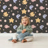 Lovely child standing in front of Whimsy Tots Bubblefish Coral Drift Wallpaper in Charcoal Gray with fish, coral, bubble, starfish in design. Lovely child standing in front of Whimsy Tots Bubblefish Coral Drift Wallpaper in Charcoal Gray with fish, coral, bubble, starfish in design.