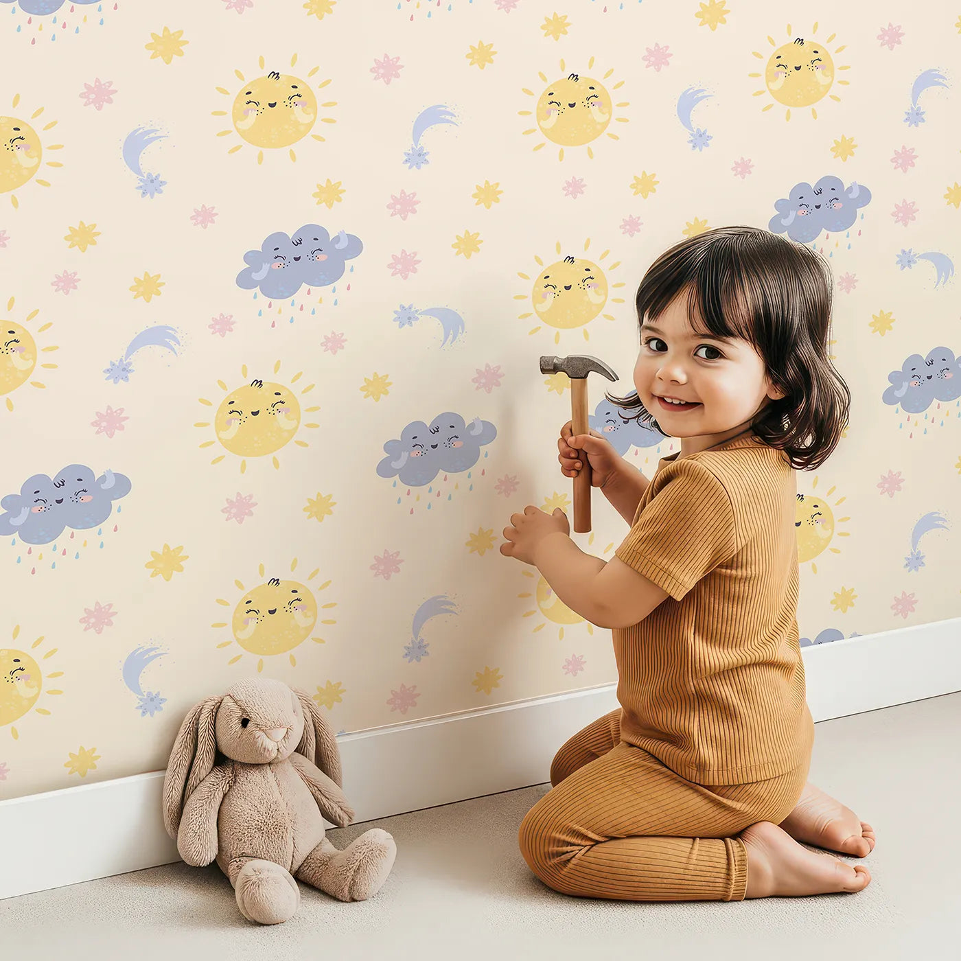 Lovely child standing in front of Whimsy Tots Sun and Cloud Kiss Wallpaper in Vanilla with sun, cloud, raindrop, flower, star in design.