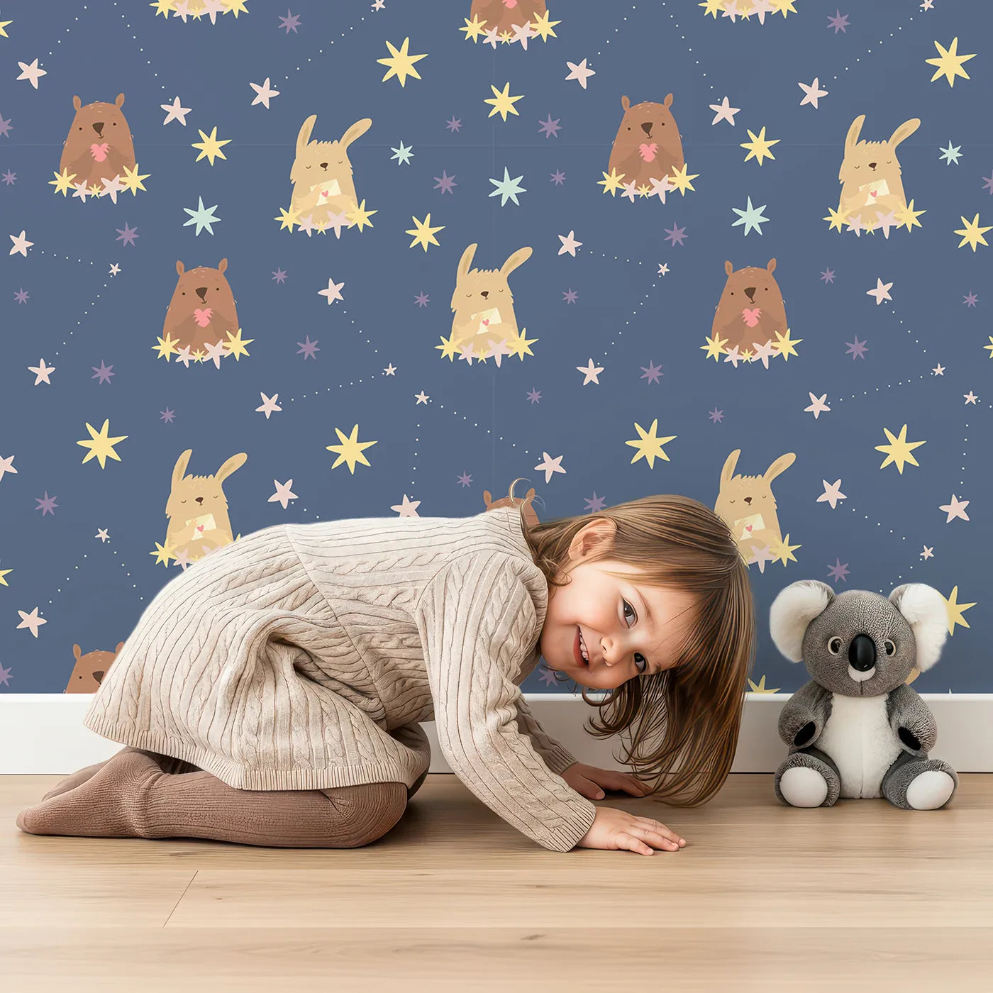 Lovely child standing in front of Whimsy Tots Starry Snuggle Pals Wallpaper in Navy Blue with bear, rabbit, star, heart, constellation in design.