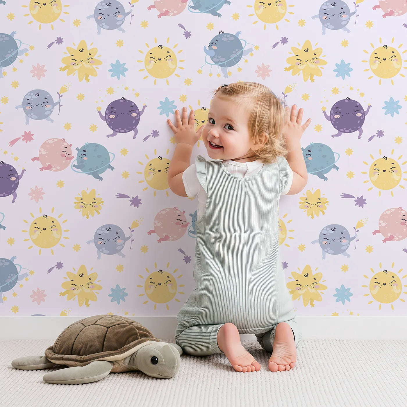 Lovely child standing in front of Whimsy Tots Planet Pals Orbit Parade Wallpaper in Lilac Lavender with planet, sun, moon, star, comet in design.