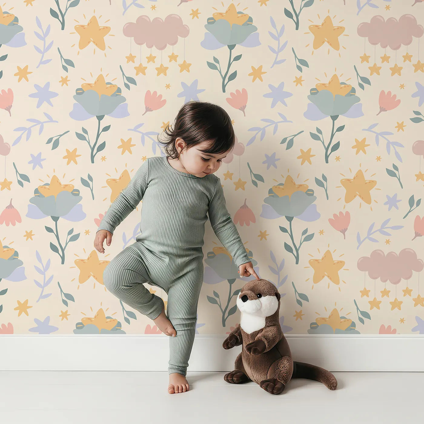 Lovely child standing in front of Whimsy Tots Starlight Blossom Dreams Wallpaper in Vanilla Cream with star, flower, cloud, leaf in design.
