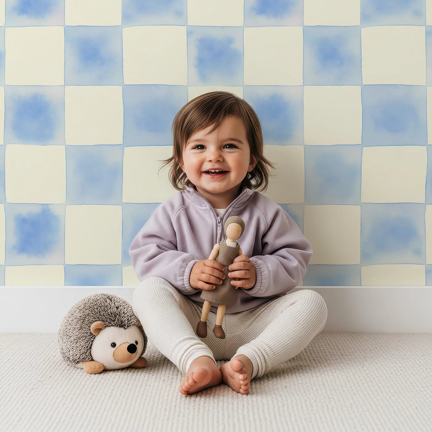 Lovely child standing in front of Whimsy Tots Gingham Watercolor Grid Wallpaper in Blueberry with checkerboard, square, watercolor in design.