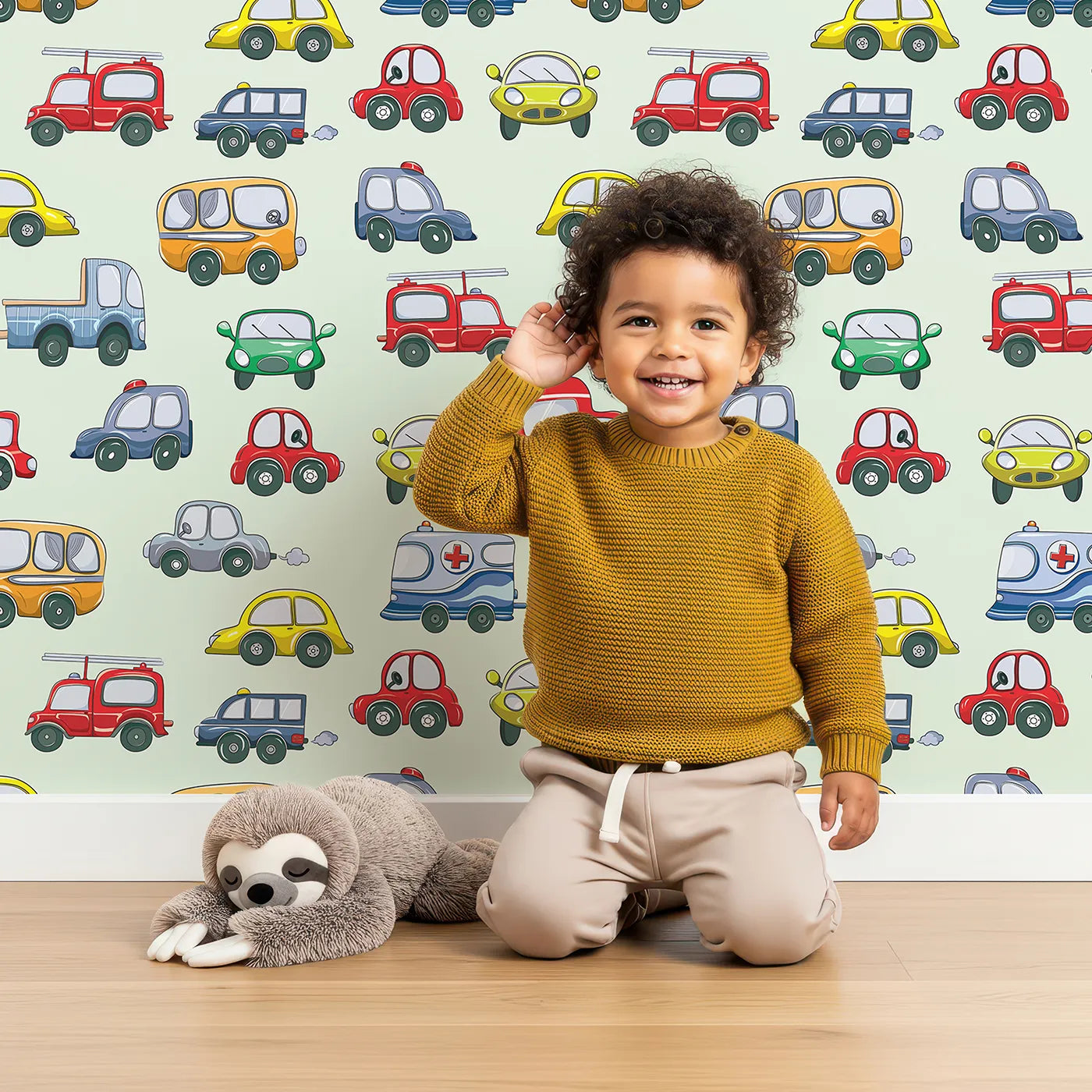 Lovely child standing in front of Whimsy Tots Tiny Wheels Parade Wallpaper in Mint Green with car, truck, bus, firetruck, ambulance in design.
