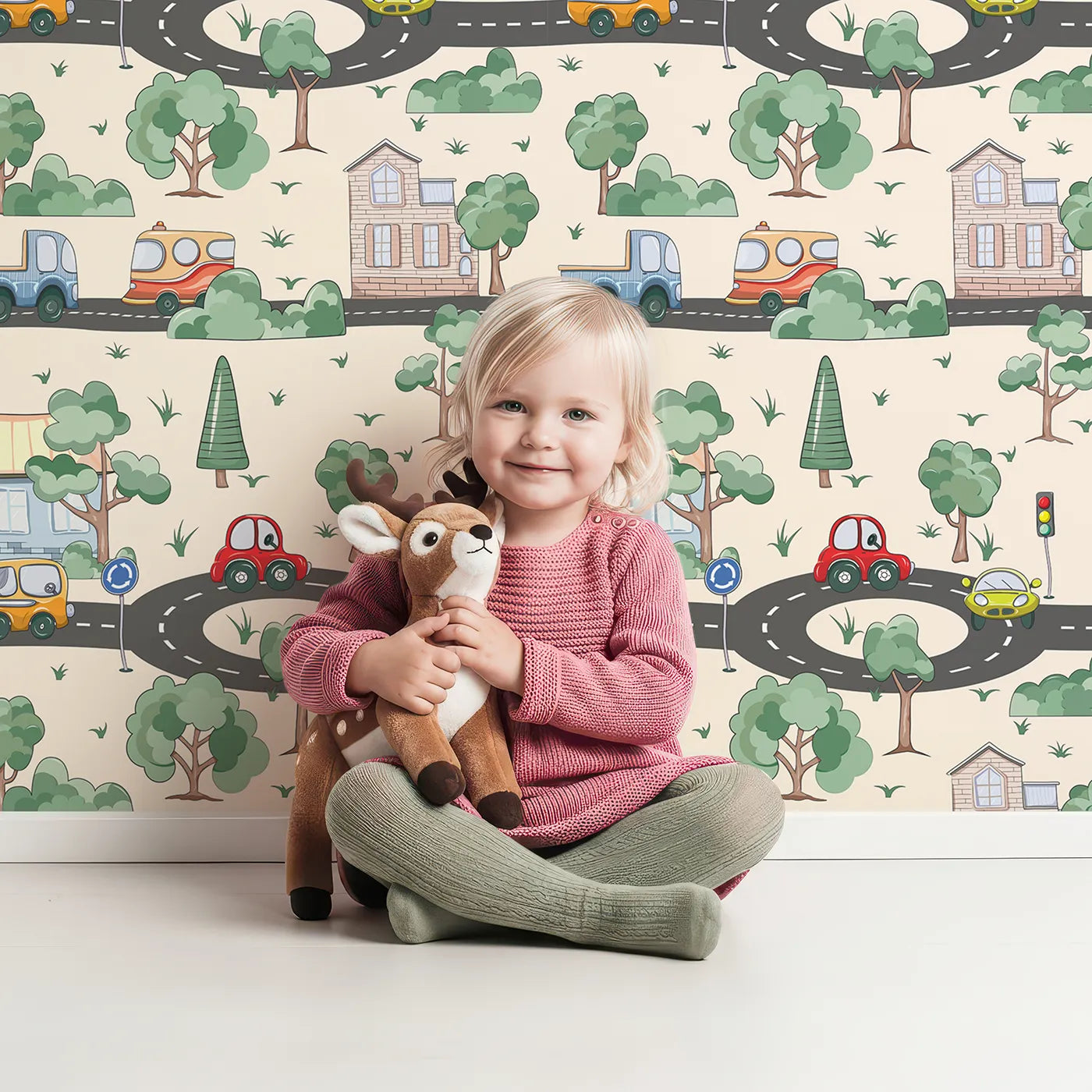 Lovely child standing in front of Whimsy Tots Bumper Buddies Town Tour Wallpaper in Cream with car, house, road, tree, stoplight in design.