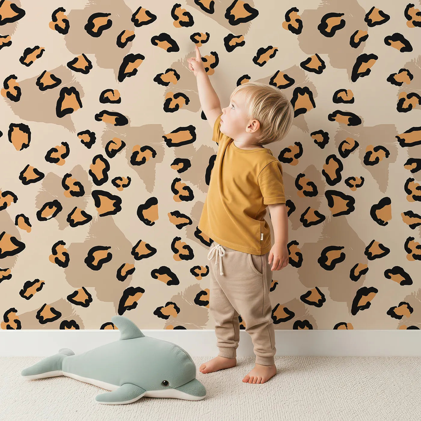 Lovely child standing in front of Whimsy Tots Playful Cub Spots Wallpaper in Beige with leopard, spot, pattern in design.