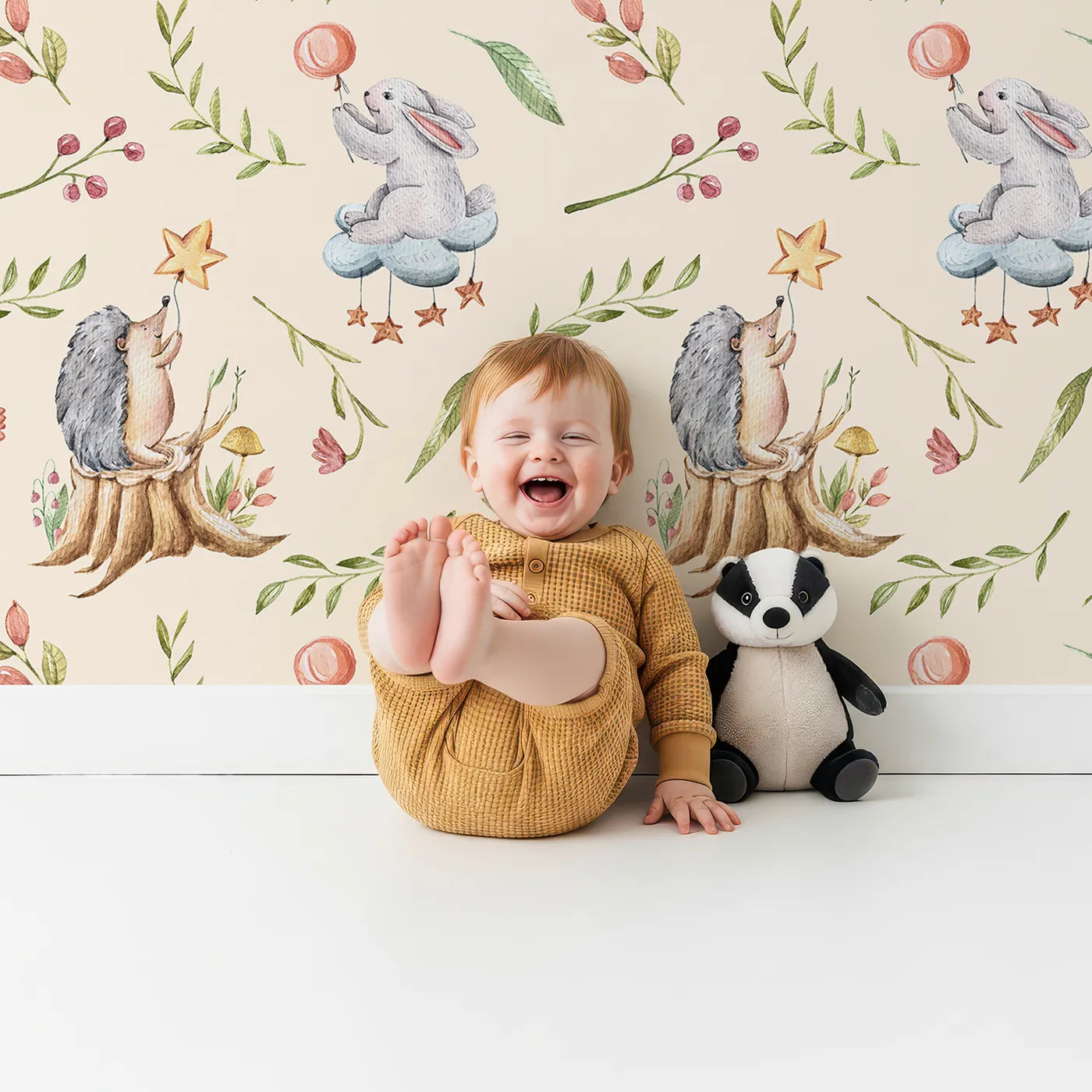Lovely child standing in front of Whimsy Tots Starlight Forest Friends Wallpaper in Blush Pink with rabbit, hedgehog, star, flower, leaf in design.