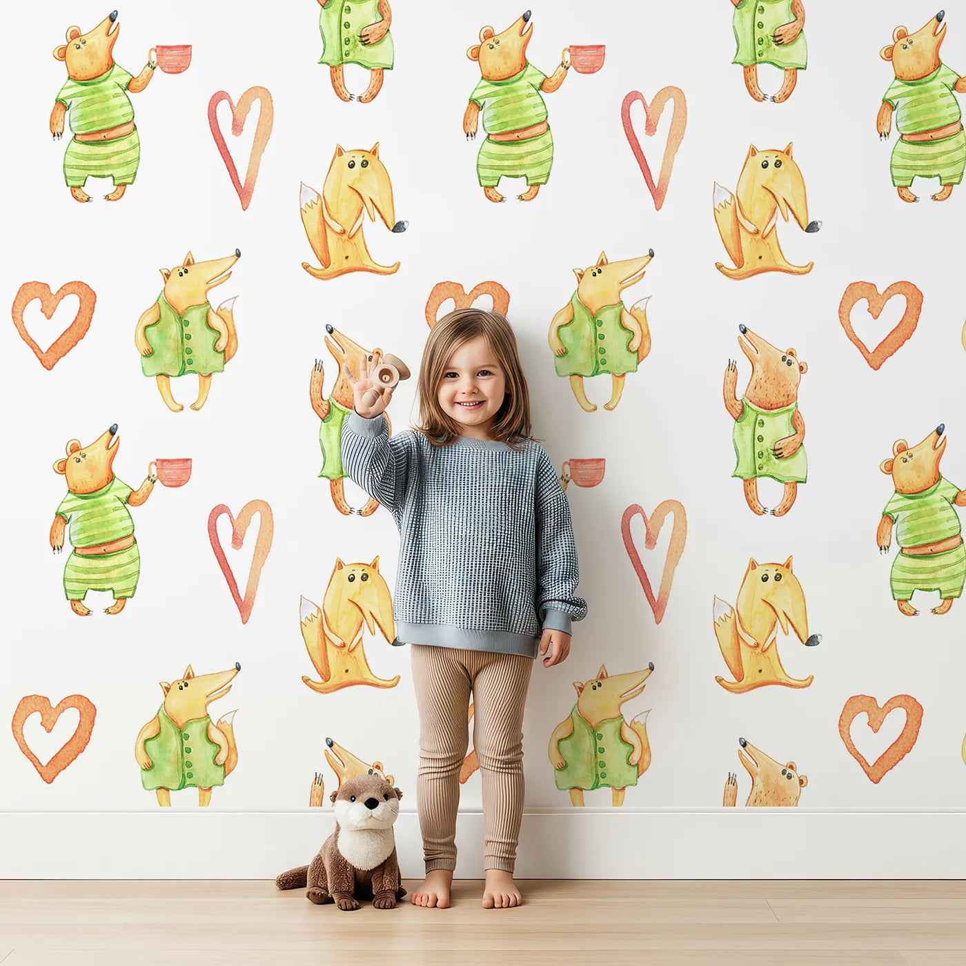 Lovely child standing in front of Whimsy Tots Heartwarming Forest Friends Wallpaper with bear, fox, heart, cup, tea in design.