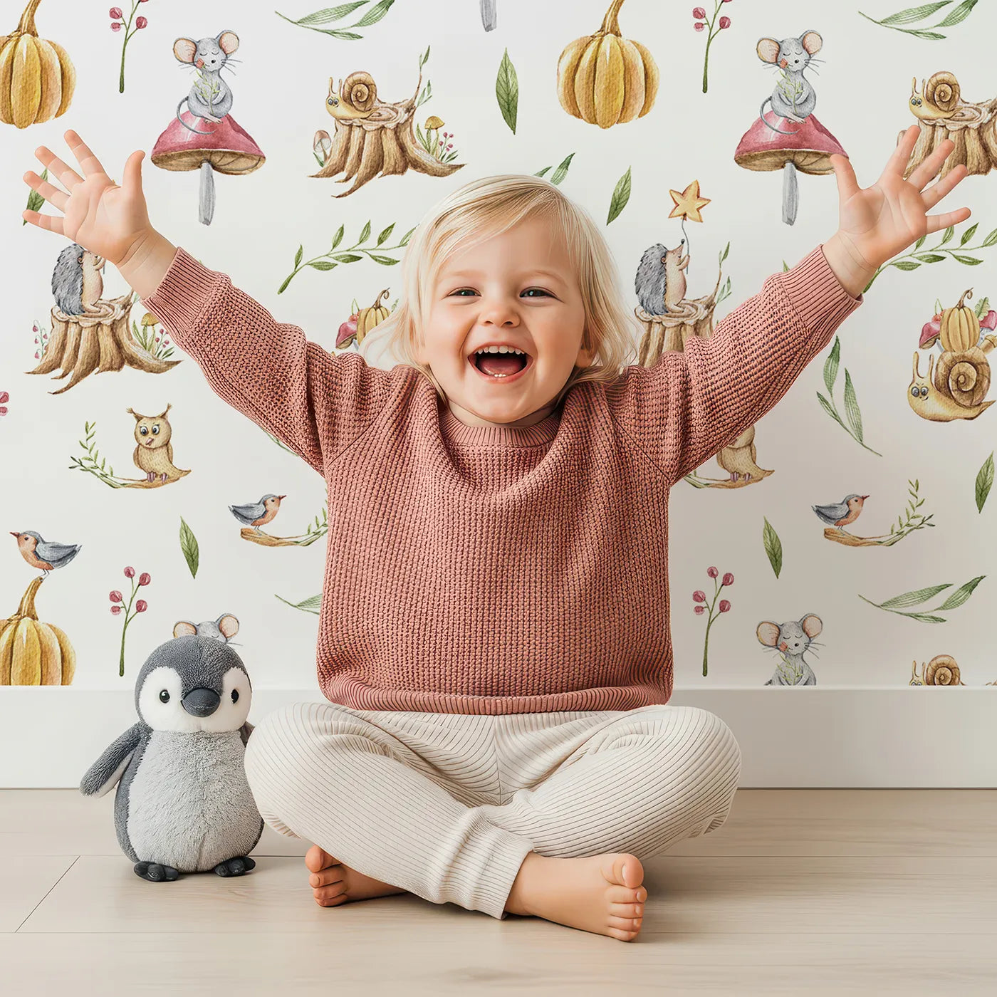 Lovely child standing in front of Whimsy Tots Wishful Woodland Friends Wallpaper in White with hedgehog, owl, mouse, snail, mushroom, leaf, pumpkin, star in design.