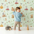 Lovely child standing in front of Whimsy Tots Wishful Woodland Friends Wallpaper in Mint Green with hedgehog, owl, mouse, snail, mushroom, leaf, pumpkin, star in design. Lovely child standing in front of Whimsy Tots Wishful Woodland Friends Wallpaper in Mint Green with hedgehog, owl, mouse, snail, mushroom, leaf, pumpkin, star in design.
