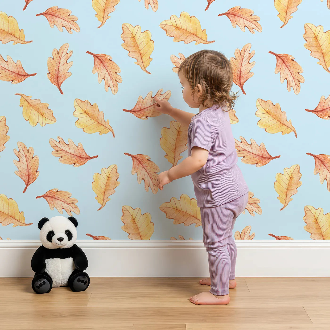 Lovely child standing in front of Whimsy Tots Falling Oak Whispers Wallpaper in Blue with oak leaf, leaf in design.