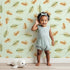 Lovely child standing in front of Whimsy Tots Acorn Meadow Whimsy Wallpaper in Mint Green with acorn, oak leaf, leaf in design. Lovely child standing in front of Whimsy Tots Acorn Meadow Whimsy Wallpaper in Mint Green with acorn, oak leaf, leaf in design.
