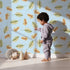 Lovely child standing in front of Whimsy Tots Acorn Meadow Whimsy Wallpaper in Blue with acorn, oak leaf, leaf in design. Lovely child standing in front of Whimsy Tots Acorn Meadow Whimsy Wallpaper in Blue with acorn, oak leaf, leaf in design.